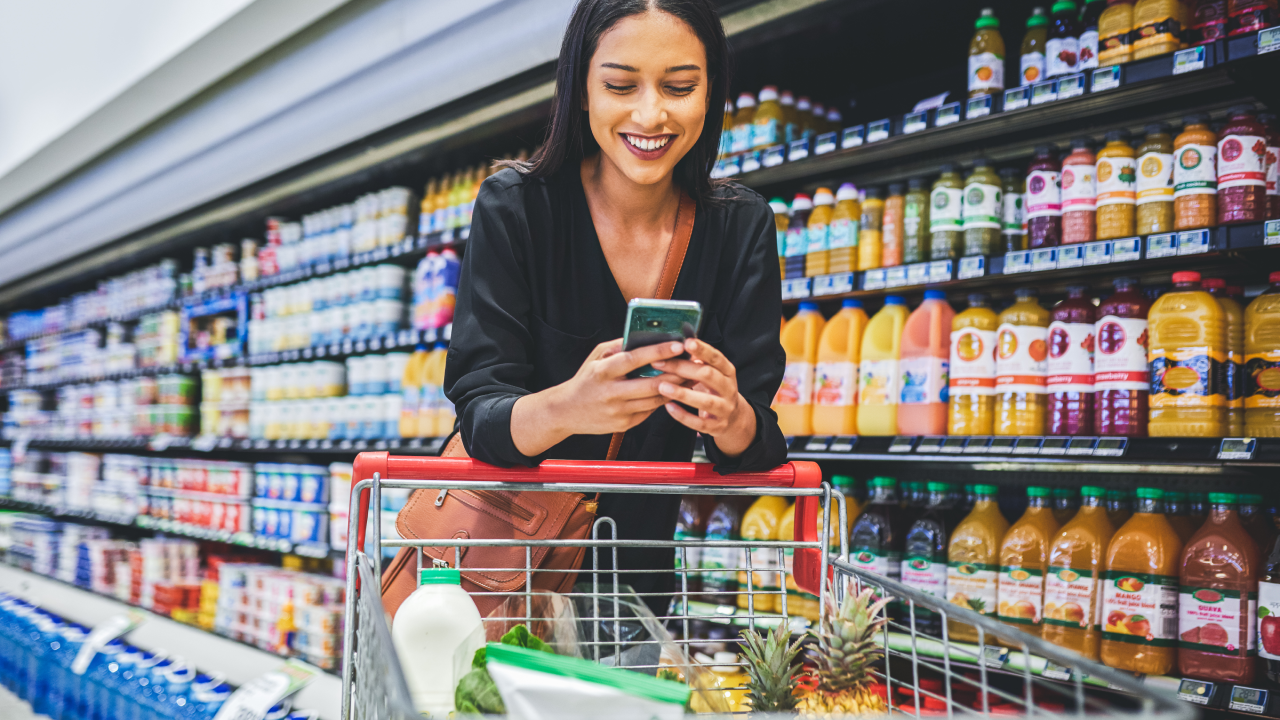 Shot of a young woman using a smartphone while shopping in a grocery store