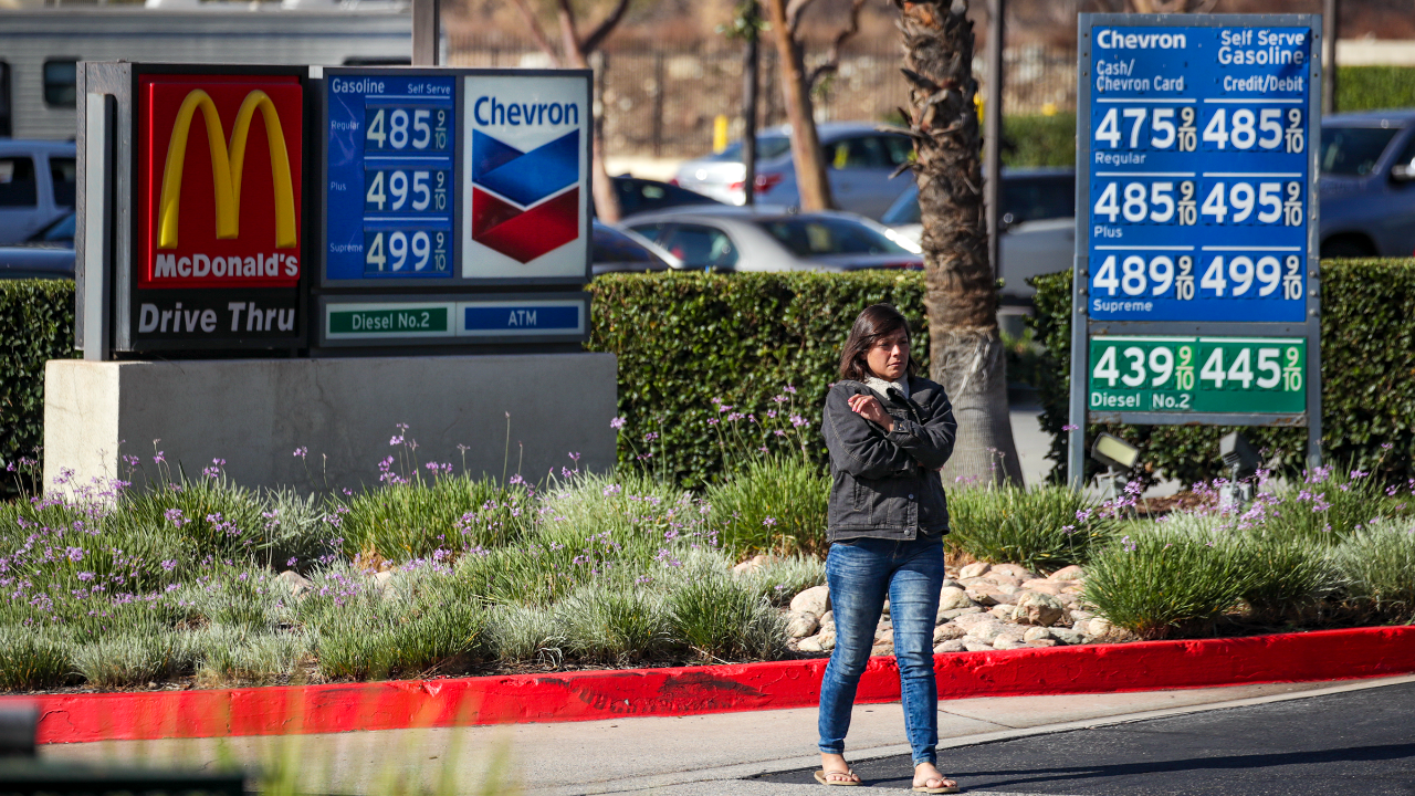Woman stands in California at the gas pump where gas prices are at least $4.75 per gallon