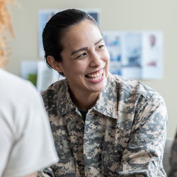 Woman in military uniform sits at a desk