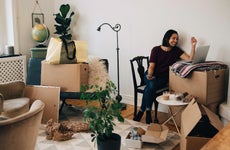 Smiling woman looking at laptop surrounded by boxes