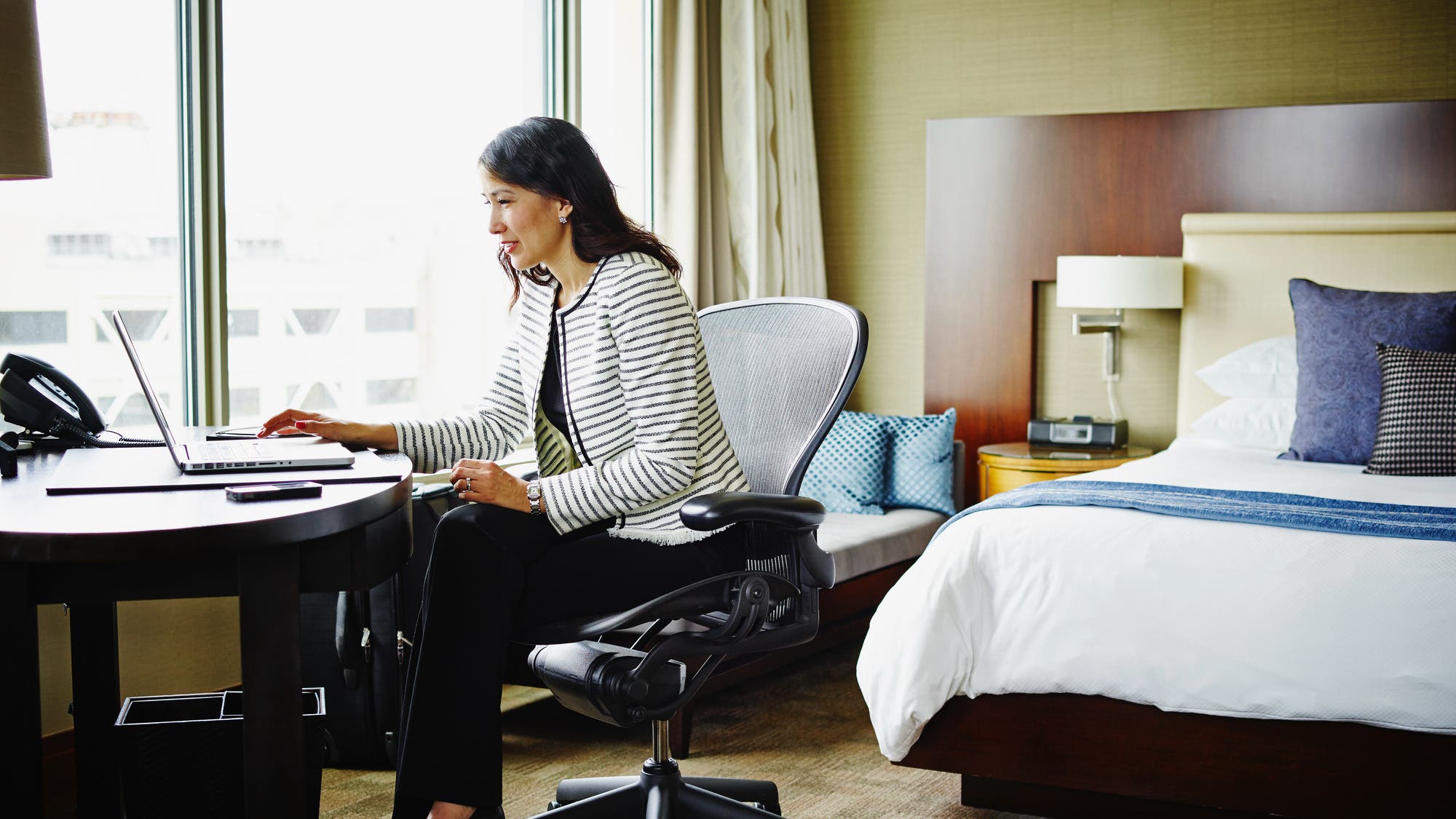 Businesswoman in hotel room working on laptop