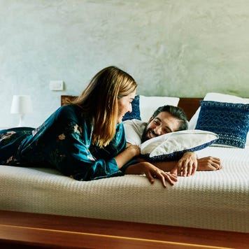 Smiling couple relaxing on bed at luxury hotel