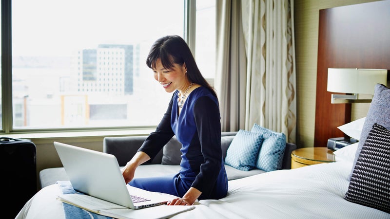 Smiling businesswoman working on laptop in hotel room