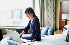 Smiling businesswoman working on laptop in hotel room