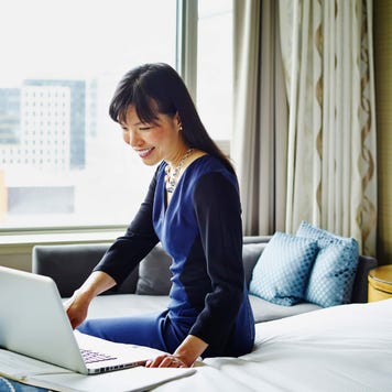 Smiling businesswoman working on laptop in hotel room