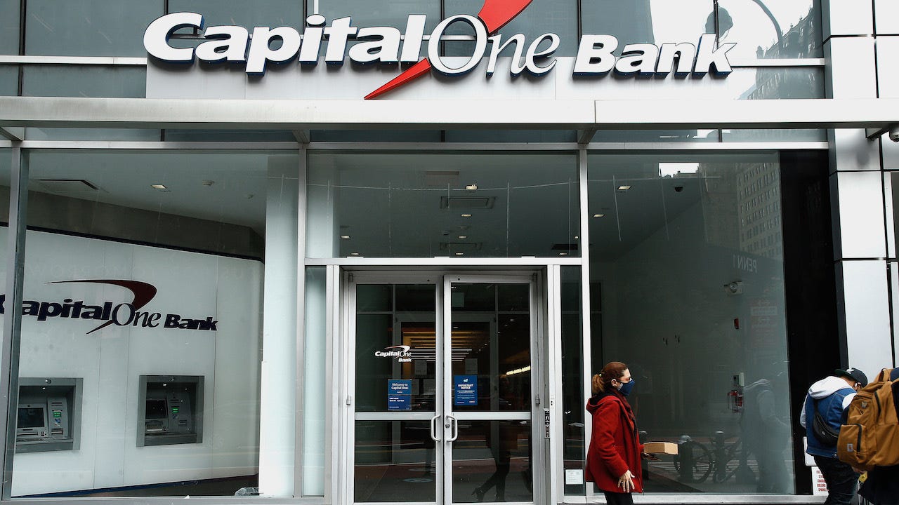 Two people are in front of a Capital One Bank.