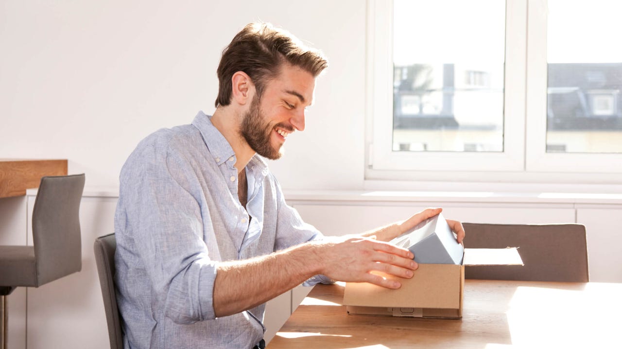 Young man sitting at a table unpacking cardboard box