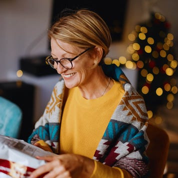 Smiling woman unpacking parcel sitting at home