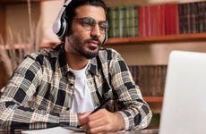 Man works at a laptop while wearing headphones