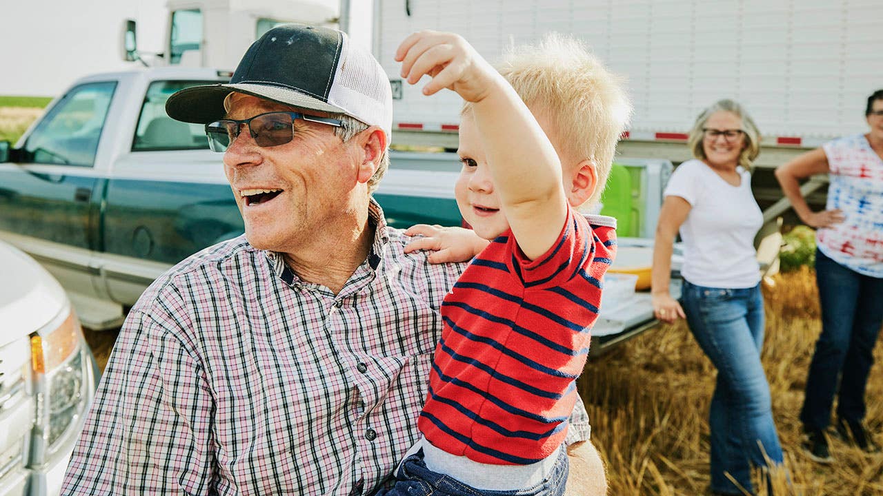 laughing farmer holding grandson