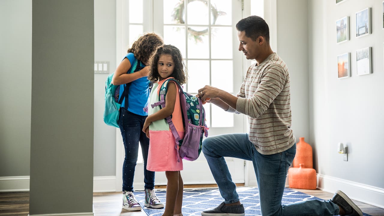 Father packing daughters backpacks for school