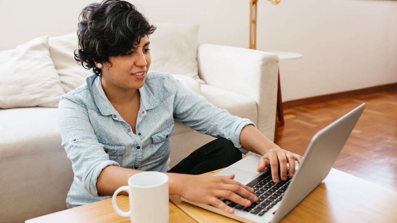 Woman sitting on floor and working on laptop. Female sitting at table with cup of coffee and using laptop.