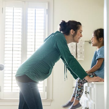 Mother talking to daughter on bathroom counter