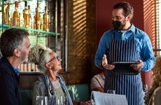 Waiter advising senior woman in restaurant
