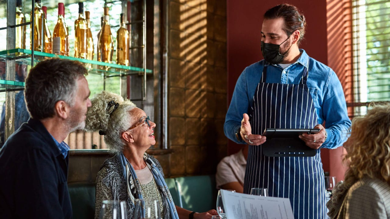 Waiter advising senior woman in restaurant