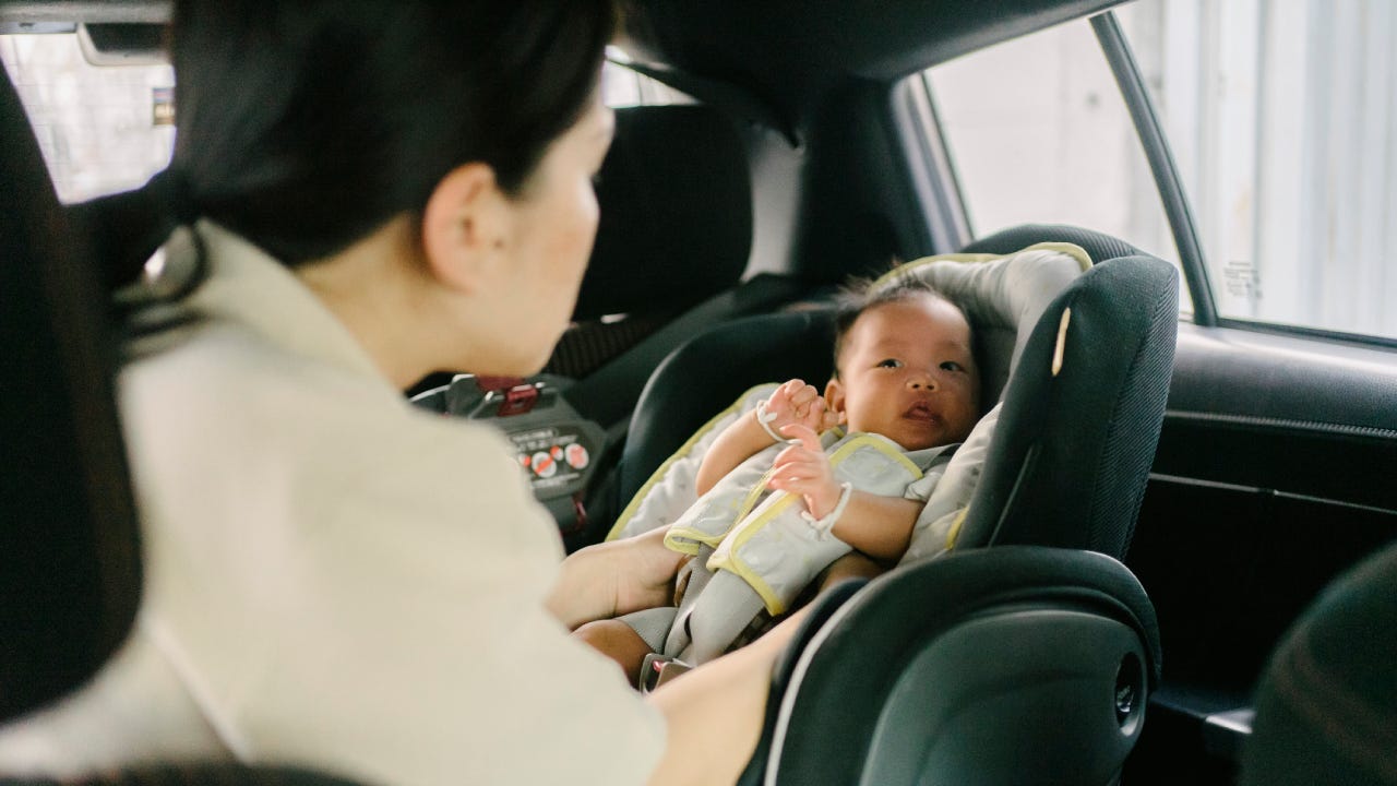 Asian adult mother prepare car safety seat for newborn baby before travel