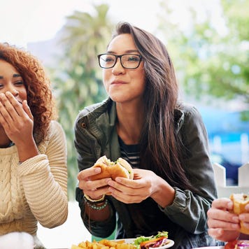 Three friends laughing and eating at an outdoor restaurant