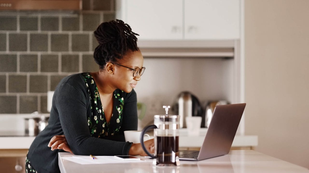 Adult woman using laptop in her kitchen