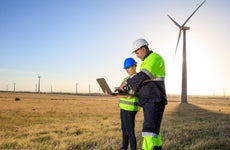 Two engineers stand in a field of windmills