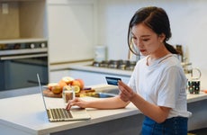 Young woman using a credit card at home to online shop