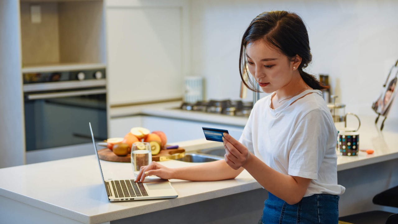 Young woman using a credit card at home to online shop