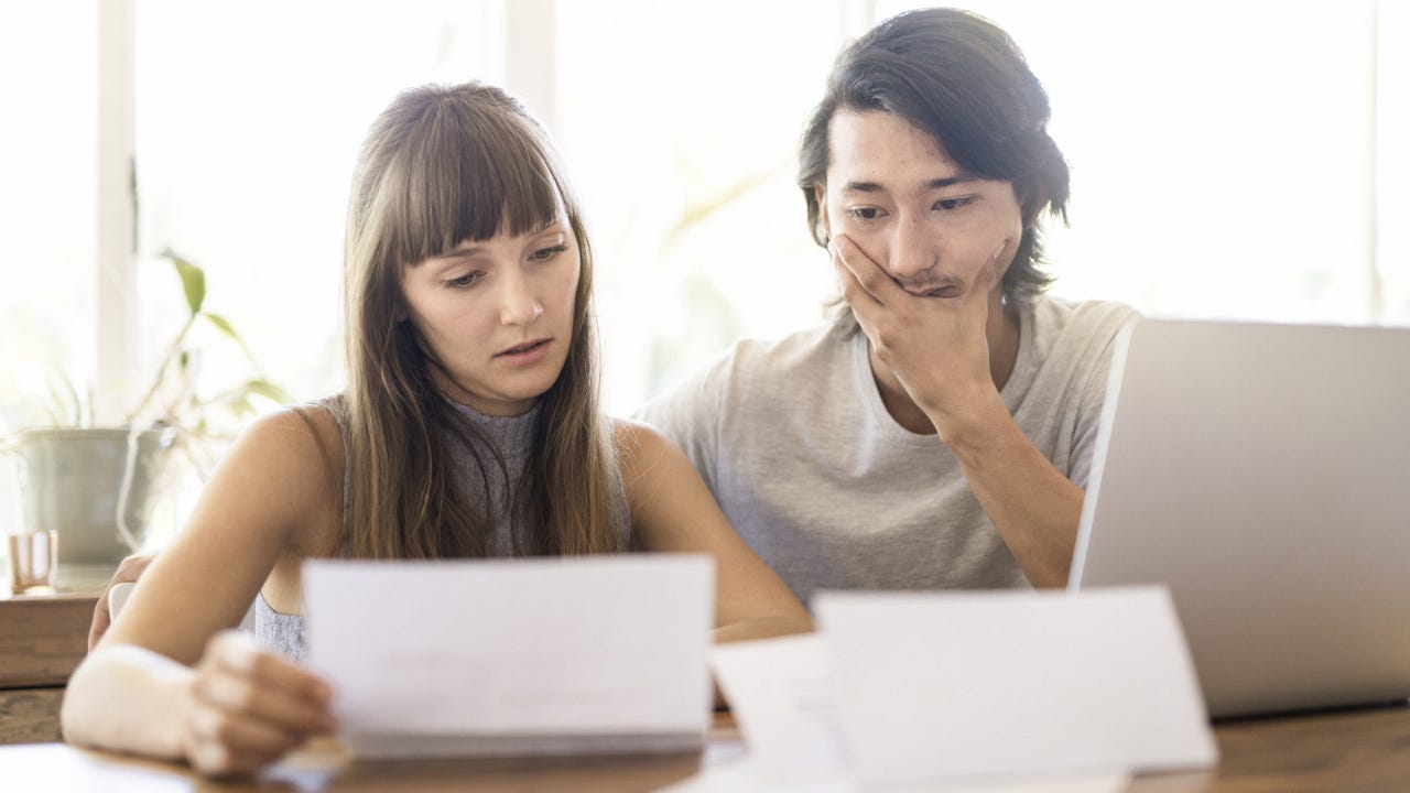 Tensed young couple reading document at home
