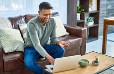 Man using a laptop and credit card on the sofa at home