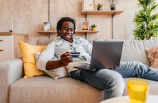 Man shopping from couch with credit card and laptop