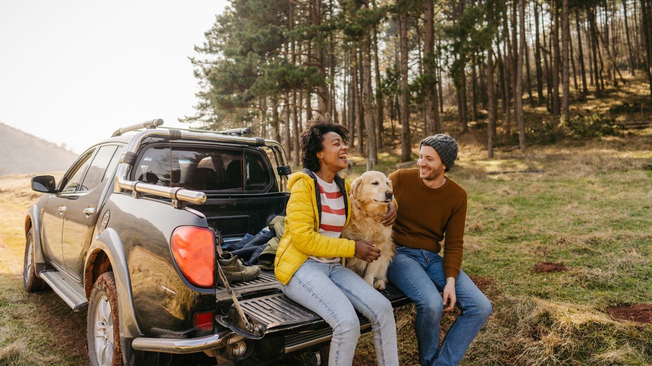 couple sitting in the back of their truck with the dog