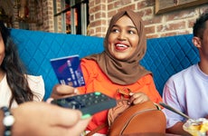 women wearing hijab hands over her credit card to pay at a restaurant
