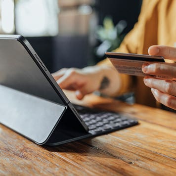 close up of hand holding credit card and typing on a digital tablet