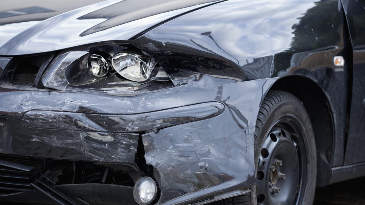 Damaged car with distorted reflection of town