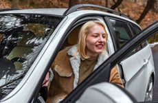 young woman getting out of car from driver's seat