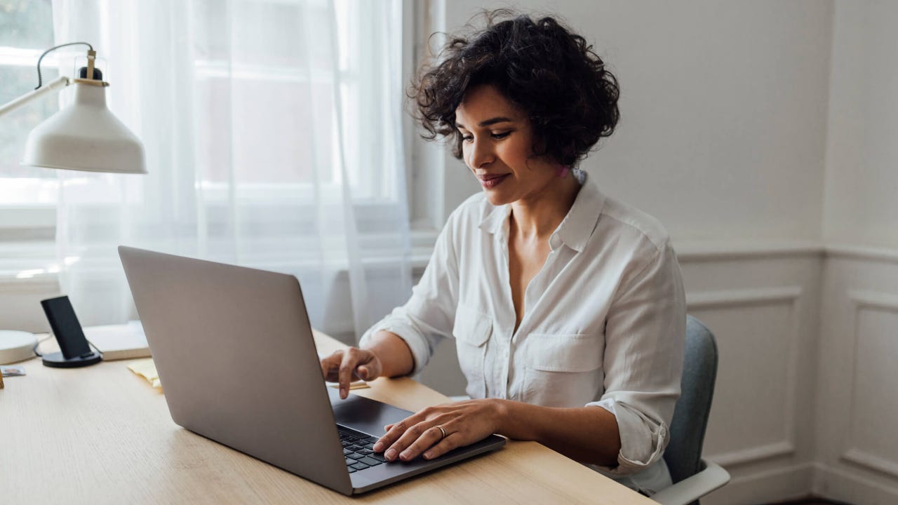 Young woman sitting at home using her laptop