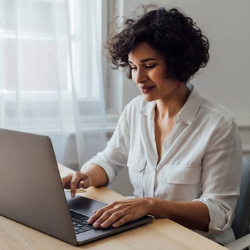 Young woman sitting at home using her laptop