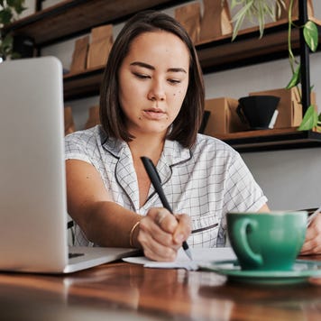 Shot of a young woman using a laptop in a cafe