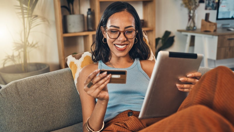 Smiling woman using credit card for ecommerce on digital tablet at home