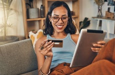 Smiling woman using credit card for ecommerce on digital tablet at home