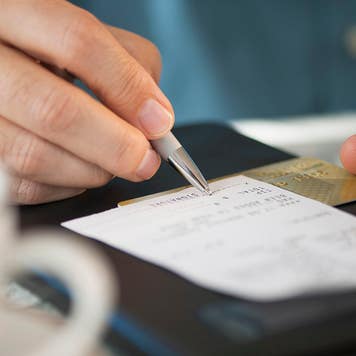 a close up of a person signing a bill