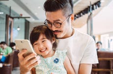 Young dad using smartphone with little daughter