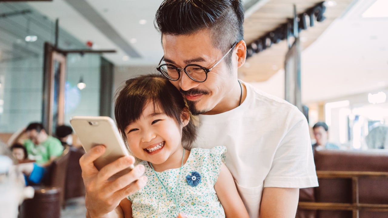 Young dad using smartphone with little daughter