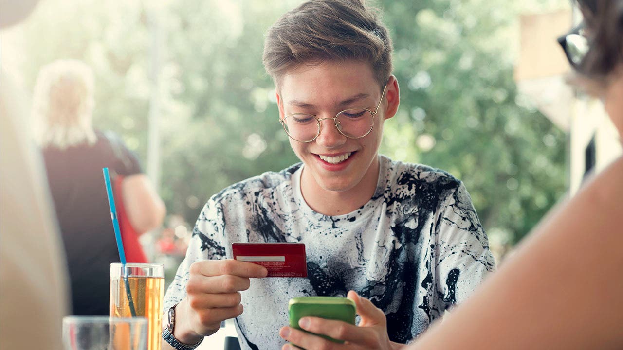 teenage boy using a credit card at a restaurant