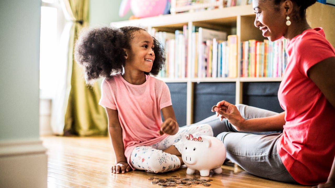 Mother and daughter putting money in piggy bank