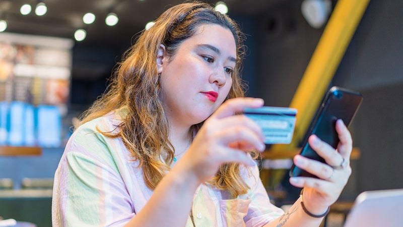 a young woman looking at a phone and credit card