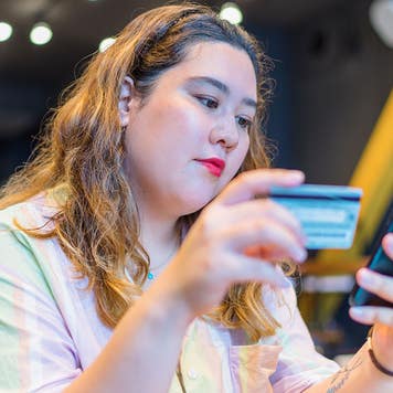 a young woman looking at a phone and credit card