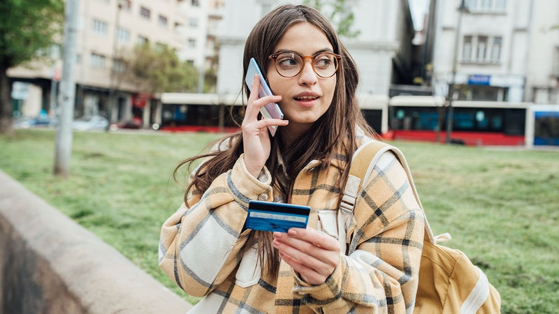 A young woman on the phone holding a credit card