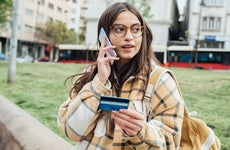 A young woman on the phone holding a credit card