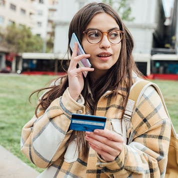 A young woman on the phone holding a credit card