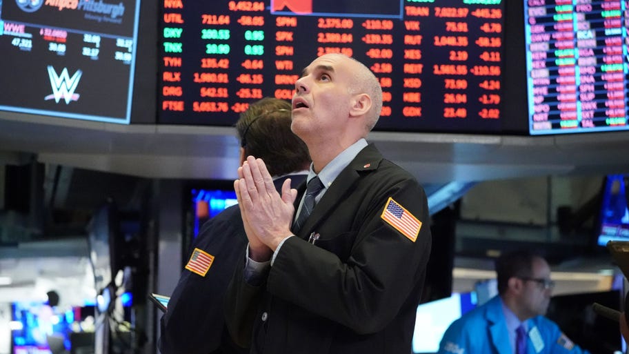 A stock trader seems to pray on the trading floor