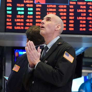 A stock trader seems to pray on the trading floor